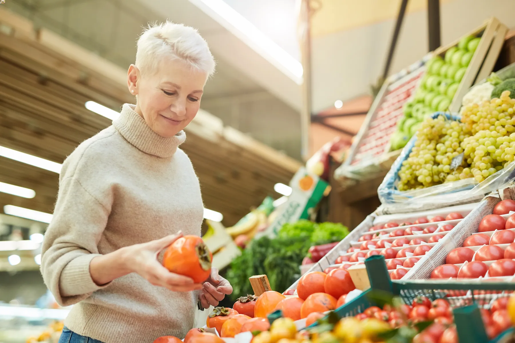 Portretfoto van vrouw die boodschappen aan het doen is en verse groente vasthoudt.